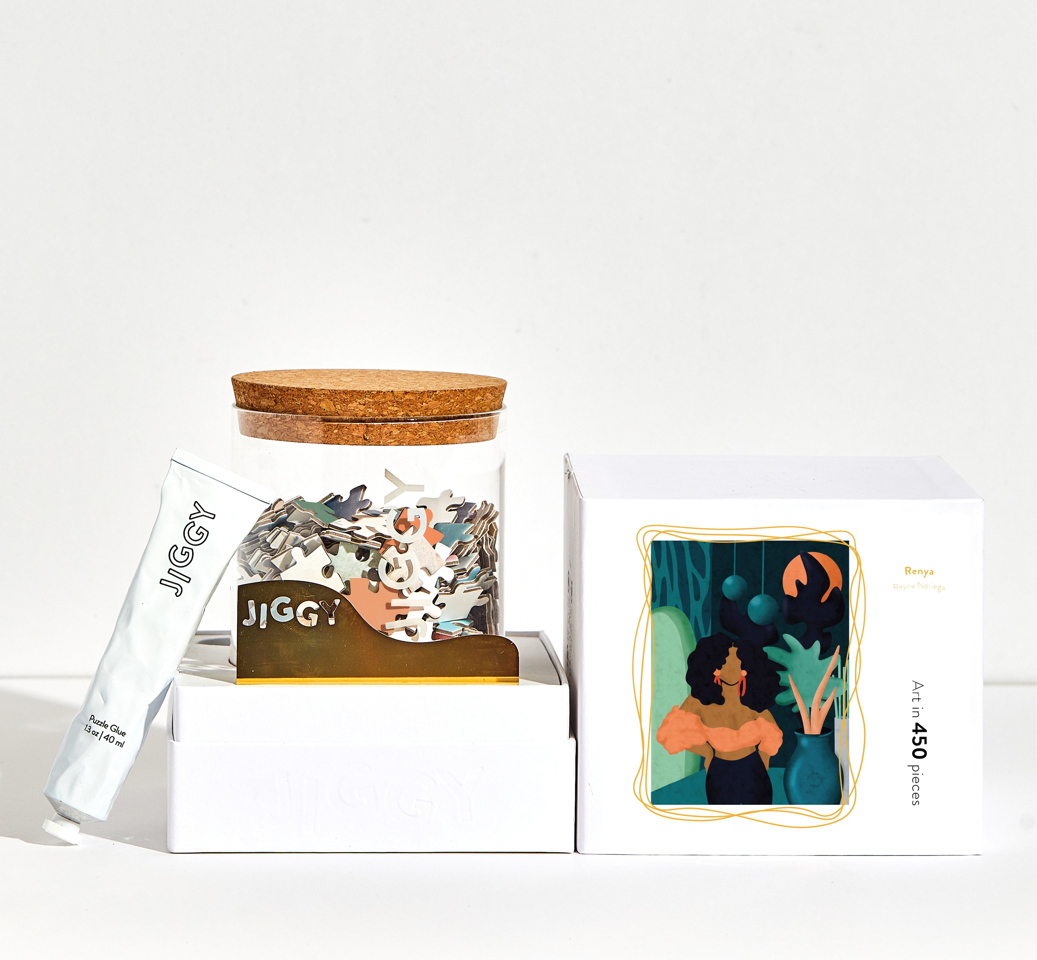 Reyna artwork puzzle box with reusable glass jar, tube of puzzle glue and straight-edge tool to spread the glue.