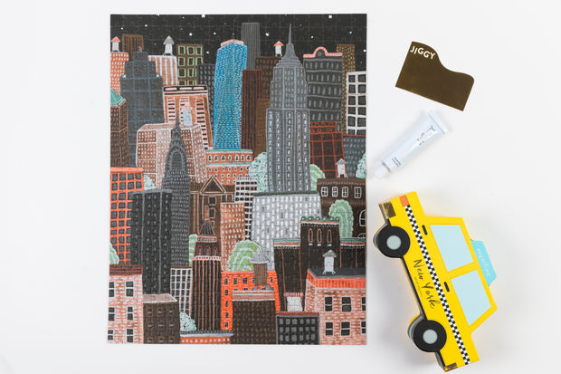 Near completed puzzle with a toy taxi alongside the NYC Night