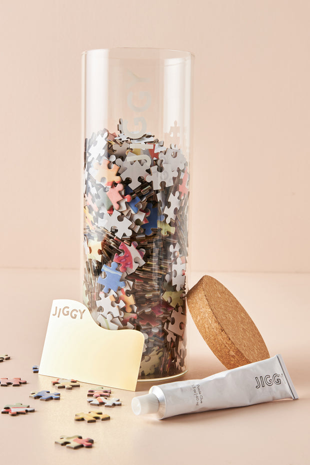 Glass jar filled with Picnic a la Plage pieces accompanied by puzzle glue and a straight edge tool
