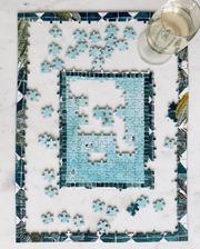 Half-completed Swim Club puzzle on marble table with glass of wine. 